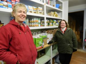 two volunteers stocking food shelves